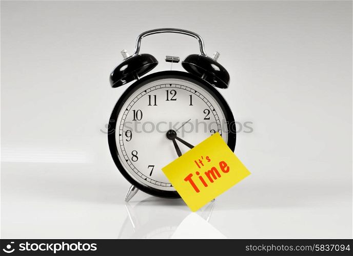 Alarm clock with a yellow note saying it&rsquo;s time