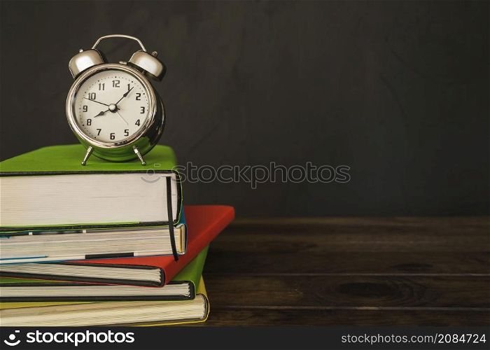 alarm clock with books pile desk