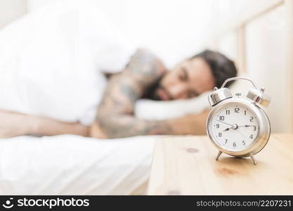 alarm clock wooden desk with man sleeping background