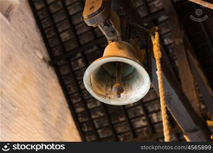 alarm concept - close up of old bell hanging under barn or factory roof. close up of old bell