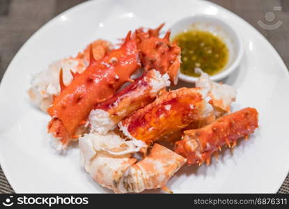 alaskan king crab and seafood on white dish with seafood sauce