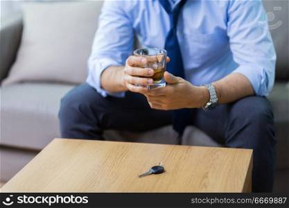 alcohol abuse, drunk driving and people concept - close up of male driver hands with whiskey glass and car key on table. close up of hands with alcohol and car key. close up of hands with alcohol and car key