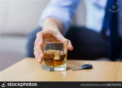 alcohol abuse, drunk driving and people concept - close up of male driver hand with whiskey glass and car key on table. close up of hand with alcohol and car key on table. close up of hand with alcohol and car key on table