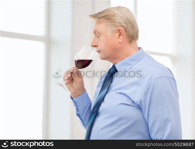 alcohol and beverage concept - older man smelling red wine