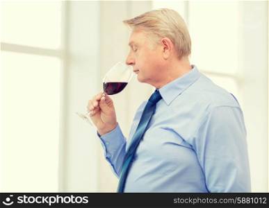 alcohol and beverage concept - older man smelling red wine