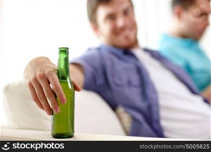 alcohol and people concept - men with beer bottles sitting on sofa at home. men with beer bottles sitting on sofa at home