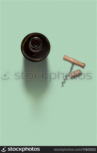 Alcohol drink wine opened bottle with natural cork and corkscrew on a light green background with soft shadows and copy space. Top view.. Opened bottle of wine with corkscrew and cork.