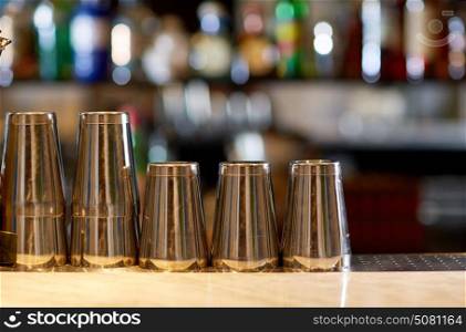 alcohol drinks and equipment concept - stainless steel shakers on bar counter. stainless steel shakers on bar counter