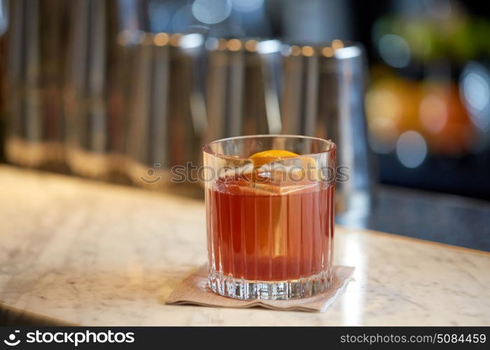 alcohol drinks and luxury concept - glass of cocktail with orange peel at bar. glass of cocktail with orange peel at bar. glass of cocktail with orange peel at bar