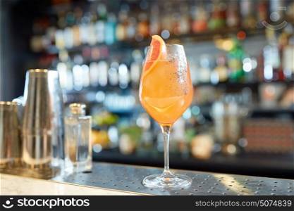 alcohol drinks and luxury concept - glass of grapefruit cocktail at bar. glass of grapefruit cocktail at bar