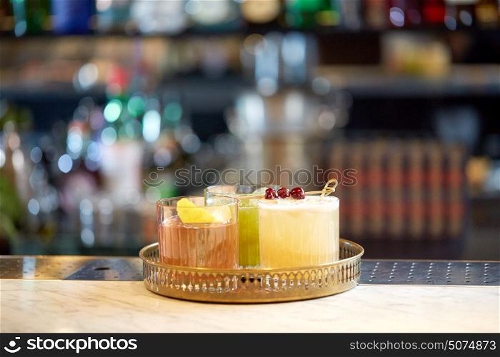 alcohol drinks and luxury concept - tray with glasses of cocktails at bar. tray with glasses of cocktails at bar