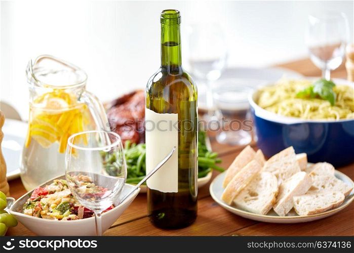 alcohol drinks, food and eating concept - bottle of wine and food on served wooden table. bottle of wine and food on served wooden table