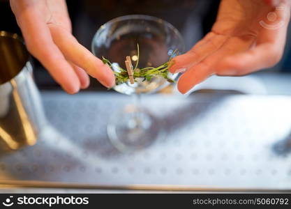 alcohol drinks, people and luxury concept - bartender hands decorating glass and preparing cocktail at bar. bartender decorating glass of cocktail at bar