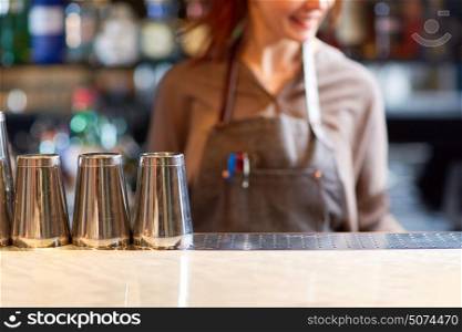 alcohol drinks, people and luxury concept - woman bartender and steel shakers at bar. woman bartender and shakers at bar