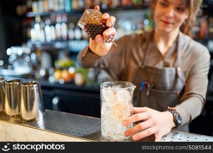 alcohol drinks, people and luxury concept - woman bartender with glass of ice and syrup preparing cocktail at bar. woman bartender preparing cocktail at bar