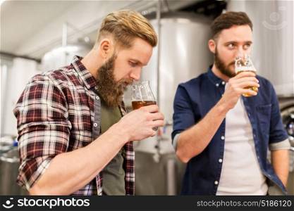 alcohol production, business and people concept - men drinking and testing craft beer at brewery. men drinking and testing craft beer at brewery