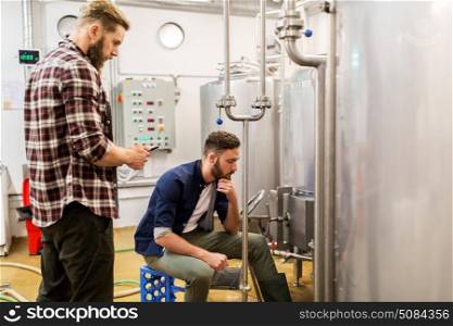 alcohol production, business and people concept - men with tablet pc computer at craft beer brewery kettle. men with tablet pc at craft beer brewery kettle. men with tablet pc at craft beer brewery kettle