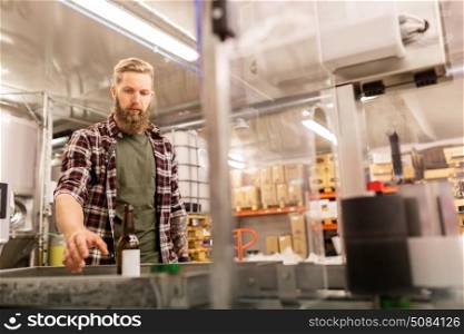 alcohol production, small business and people concept - man with bottle at craft beer brewery. man with bottle at craft beer brewery. man with bottle at craft beer brewery