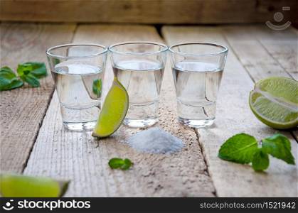 Alcohol Shot Drink. Silver Tequila with Lime, Salt and Green on the Wooden Table.. Alcohol Shot Drink. Silver Tequila with Lime, Salt and Green on the Wooden Table
