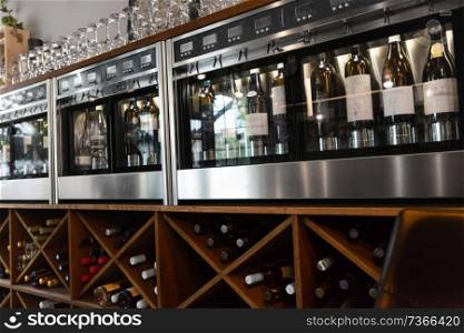 alcohol, technology and storage concept - close up of wine bottles storing in dispenser at bar or restaurant. close up of wine bottles in dispenser at bar