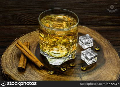 Alcoholic beverage with cinnamon and ice on a wooden background.