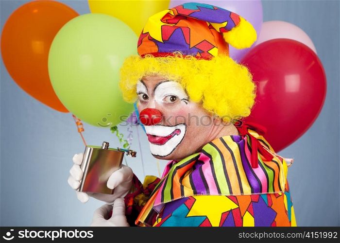 Alcoholic clown sneaks a drink from his flask.