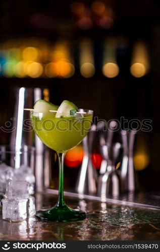 Alcoholic cocktail of green color on a bar counter. Cucumber cocktail.