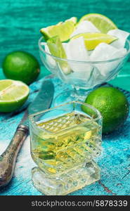 alcoholic cocktail with lime. Glass with alcohol and fruits of lime and the bowl with ice on wooden background