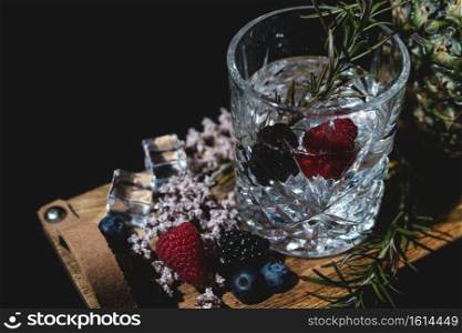 alcoholic drink with berries and ice on a old wooden table