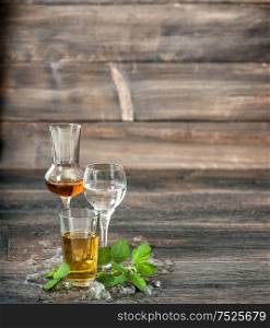 Alcoholic drinks with ice and mint leaves on wooden background. Aperitif, whiskey, liquor, vodka