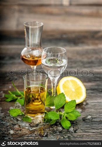 Alcoholic Drinks with ice, lemon and mint leaves on wooden background. Food beverages