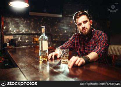Alcoholic sitting at the bar counter and drinks strong alcohol beverages. Male person in pub, alcoholism, drunkenness. Alcoholic sitting at bar and drinks strong alcohol