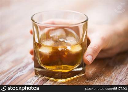 alcoholism, alcohol addiction and people concept - close up of male hand with glass of whiskey on table. male hand with glass of alcohol on table. male hand with glass of alcohol on table