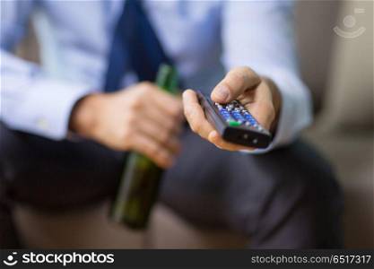 alcoholism, alcohol addiction and people concept - close up of man with tv remote drinking beer. close up of man with tv remote drinking beer. close up of man with tv remote drinking beer