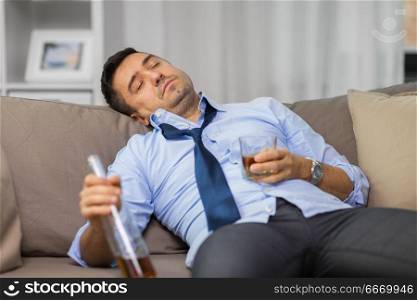 alcoholism, alcohol addiction and people concept - drunk man or alcoholic sleeping with bottle of whiskey on sofa at home. drunk man with bottle of alcohol sleeping at home. drunk man with bottle of alcohol sleeping at home