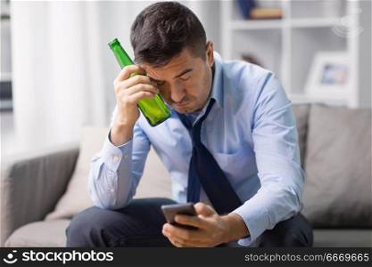 alcoholism, alcohol addiction and people concept - drunk man or male alcoholic with smartphone drinking bottled beer at home. alcoholic with smartphone drinking beer at home. alcoholic with smartphone drinking beer at home