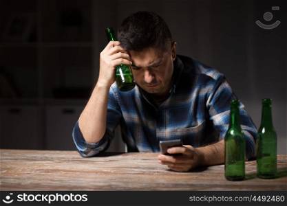 alcoholism, alcohol addiction and people concept - drunk man with smartphone and bottle of beer at night. man with smartphone and bottle of beer at night. man with smartphone and bottle of beer at night