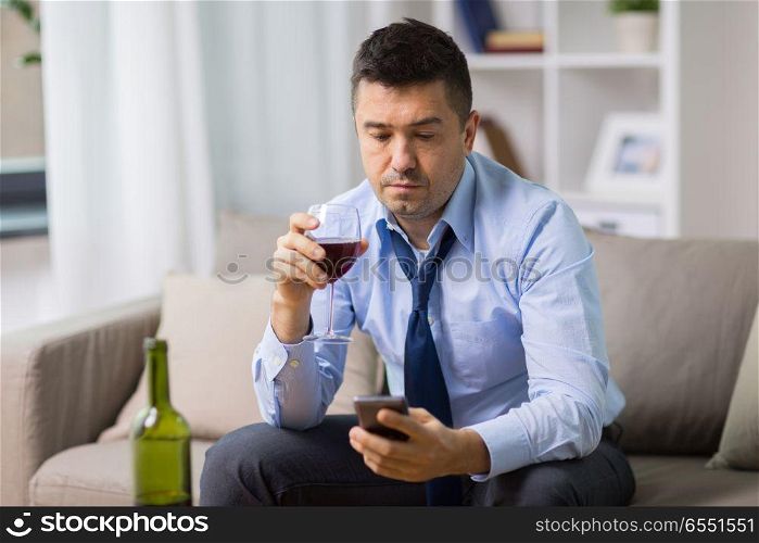 alcoholism, alcohol addiction and people concept - drunk man with smartphone and bottle of wine at home. drunk man with alcohol and smartphone at home. drunk man with alcohol and smartphone at home