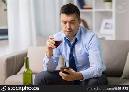 alcoholism, alcohol addiction and people concept - drunk man with smartphone and bottle of wine at home. drunk man with alcohol and smartphone at home. drunk man with alcohol and smartphone at home