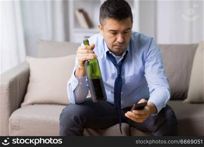 alcoholism, alcohol addiction and people concept - drunk man with smartphone and bottle of wine at home. man with smartphone and bottle of alcohol at home. man with smartphone and bottle of alcohol at home