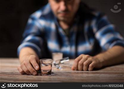 alcoholism, alcohol addiction and people concept - male alcoholic drinking shot at night. man drinking alcohol at night. man drinking alcohol at night