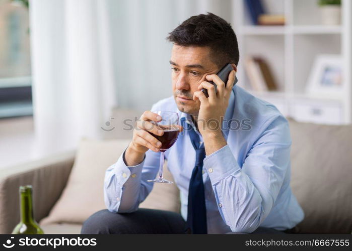 alcoholism, alcohol addiction and people concept - male alcoholic drinking wine and calling on smartphone at home. drunk man with alcohol calling on smartphone. drunk man with alcohol calling on smartphone