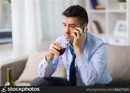 alcoholism, alcohol addiction and people concept - male alcoholic drinking wine and calling on smartphone at home. drunk man with alcohol calling on smartphone. drunk man with alcohol calling on smartphone