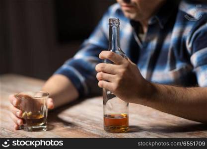alcoholism, alcohol addiction and people concept - male alcoholic with bottle and glass drinking whiskey at night. alcoholic with bottle drinking whiskey at night. alcoholic with bottle drinking whiskey at night