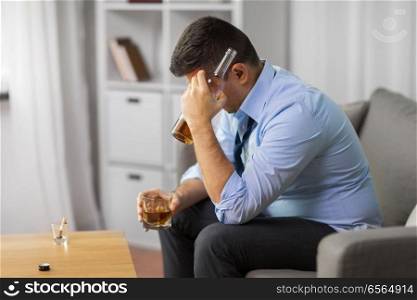 alcoholism, alcohol addiction and people concept - male alcoholic with bottle and glass drinking whiskey at home. alcoholic with bottle drinking whiskey at home