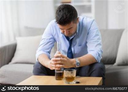 alcoholism, alcohol addiction and people concept - male alcoholic with bottle and drinking whiskey at home. alcoholic with bottle drinking whiskey at home. alcoholic with bottle drinking whiskey at home