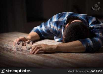 alcoholism, alcohol addiction and people concept - male alcoholic with empty glasses lying or sleeping on table at night. drunk man with empty glasses on table at night. drunk man with empty glasses on table at night