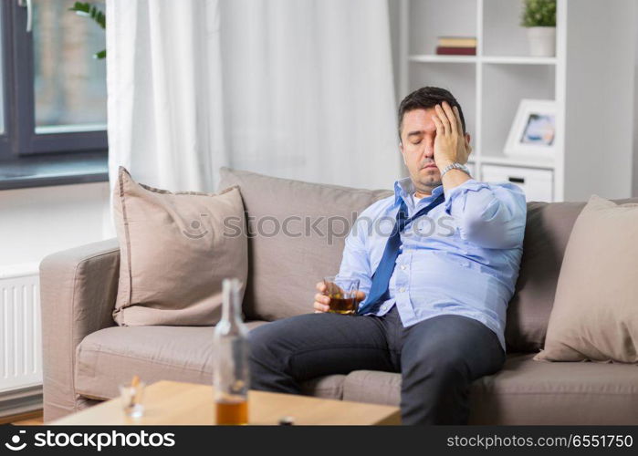 alcoholism, alcohol addiction and people concept - male alcoholic with glass drinking whiskey at home. alcoholic with glass drinking whiskey at home. alcoholic with glass drinking whiskey at home