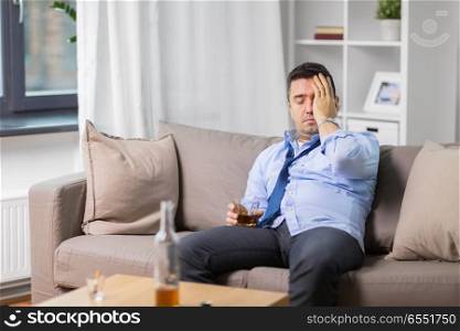 alcoholism, alcohol addiction and people concept - male alcoholic with glass drinking whiskey at home. alcoholic with glass drinking whiskey at home. alcoholic with glass drinking whiskey at home
