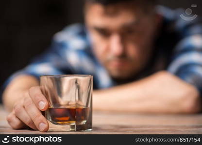 alcoholism, alcohol addiction and people concept - male alcoholic with glass of whiskey lying on table at night. drunk man with glass of alcohol on table at night. drunk man with glass of alcohol on table at night